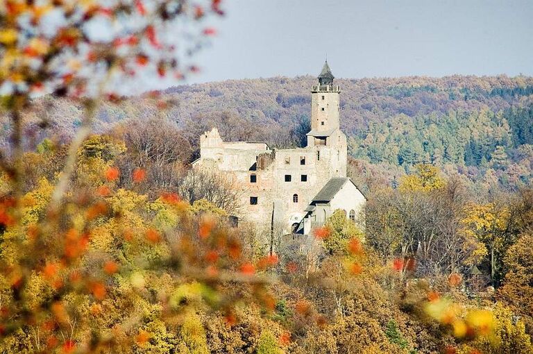 Die Burg Grodno, umgeben von herbstlich gefärbtem Wald, aus der Ferne betrachtet.