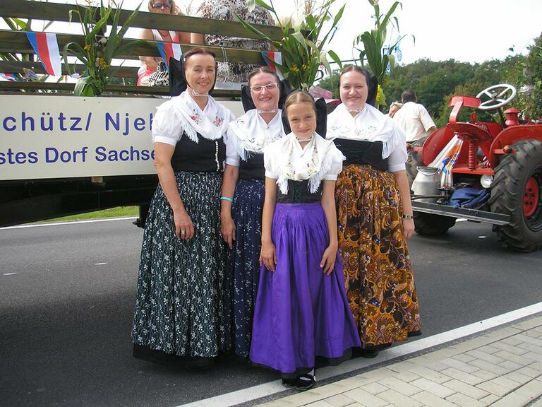 Vier Frauen verschiedener Generationen in traditionell sorbischen Trachten bei einem Festumzug.