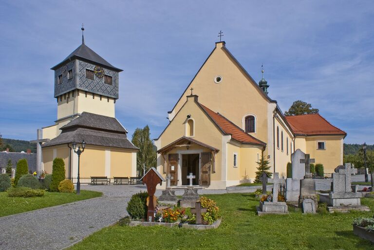 Die Schädelkapelle umgeben von vielen Gräbern. Links neben dem Hauptgebäude ragt der charakteristische Turm der Kapelle in die Höhe.