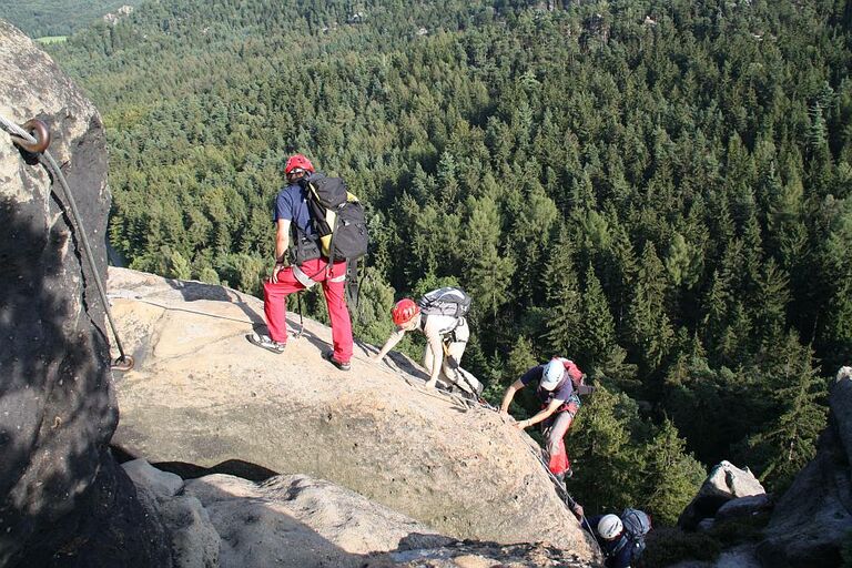 Blick von Oben auf eine Gruppe Kletterer, die einen Felsen am Nonnensteig erklimmt.