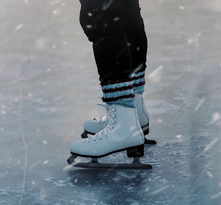 Beine eines Schlittschuhläufers auf leicht verschneitem Eis.