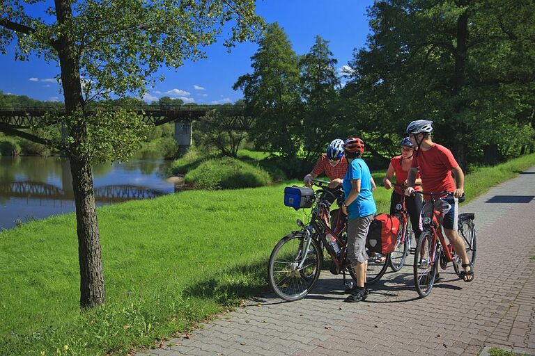 Eine Gruppe Radfahrer rastet bei sonnigem Wetter am Rand des Oder-Neisse-Radweges.