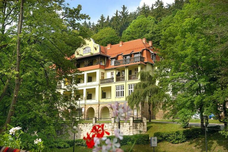 Das Sanatorium Chopin inmitten grüner Bäume bei sonnigem Wetter.