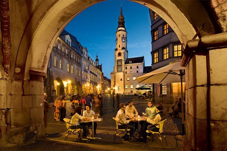 Der Görlitzer Marktplatz mit Kirche im Hintergrund zu abendlicher Stunde bei Straßenbeleuchtung.