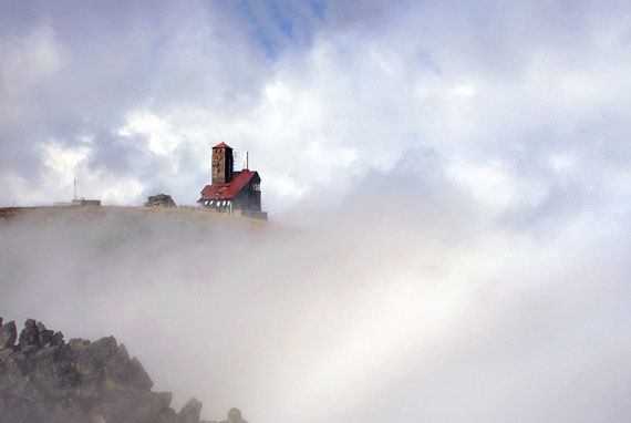 Altes Haus auf Klippe über Nebel 